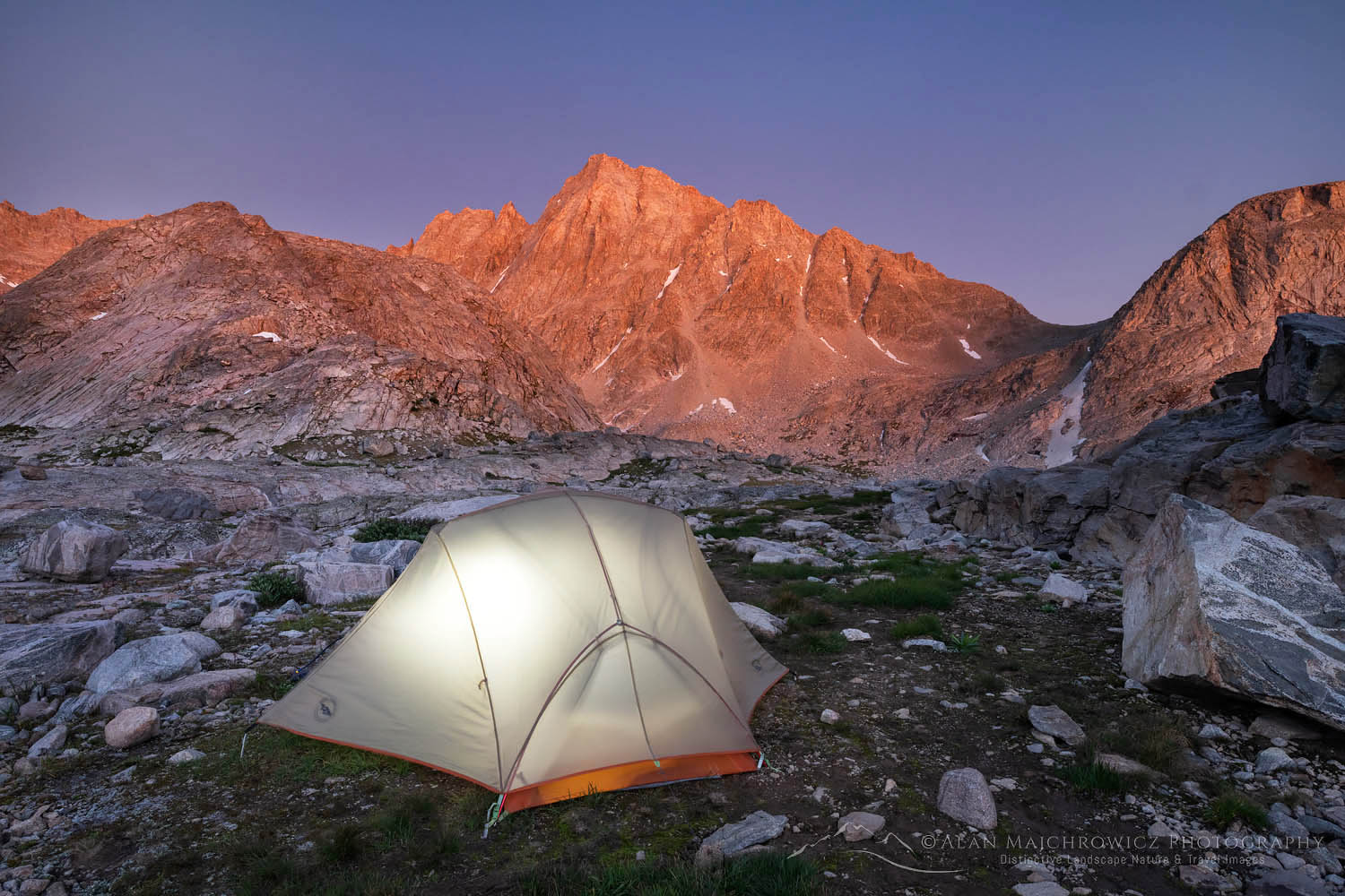 Alpenglow over backcountry camp with illuminated tent in Indian Basin, Harrower Peak is in the distance, Bridger Wilderness, Wind River Range Wyoming